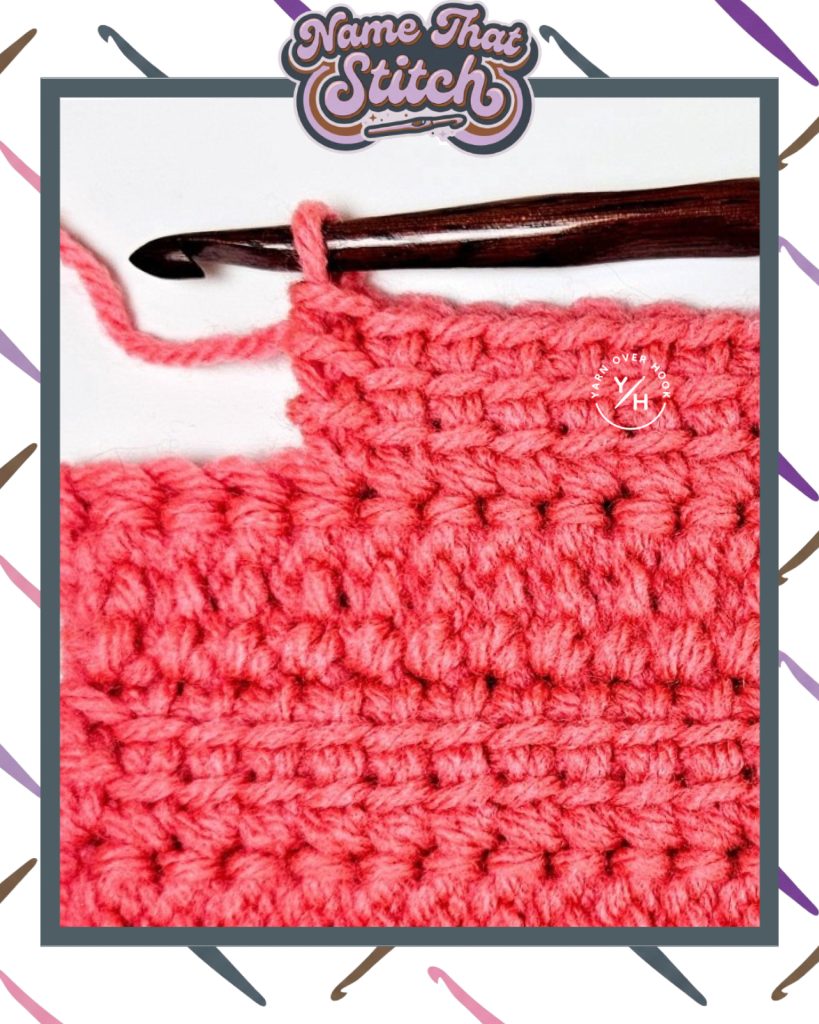 Close-up of a crochet work-in-progress showing a short row of textured stitches in pink yarn, with a wooden crochet hook and yarn ball, featured as part of the Name That Stitch daily crochet puzzle. View more at NameThatStitch.com