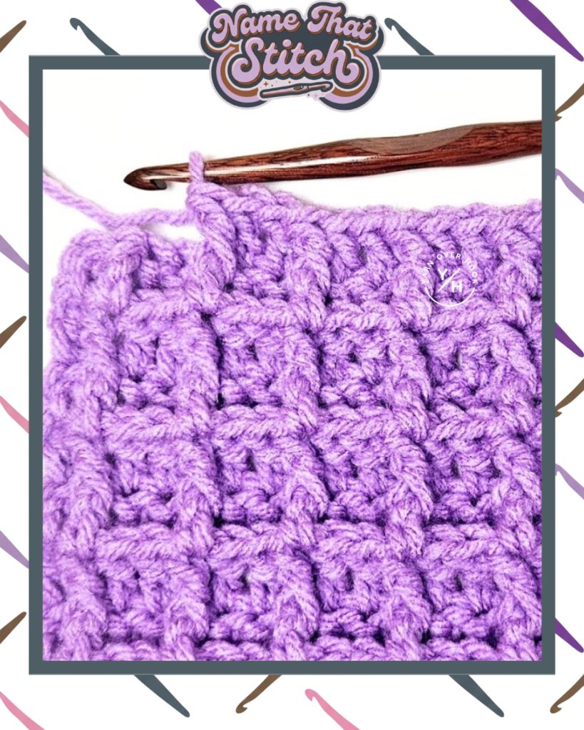 Close-up of a crochet work-in-progress showing a short row of textured stitches in purple yarn, with a wooden crochet hook and yarn ball, featured as part of the Name That Stitch daily crochet puzzle. View more at NameThatStitch.com