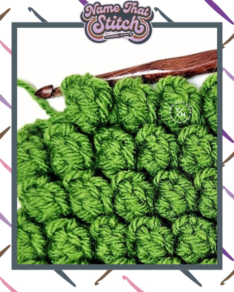 Close-up of a crocheted fabric displaying a repeating stitch pattern worked in an green yarn, with a wooden crochet hook and featured as part of the Name That Stitch daily crochet puzzle. View more at NameThatStitch.com