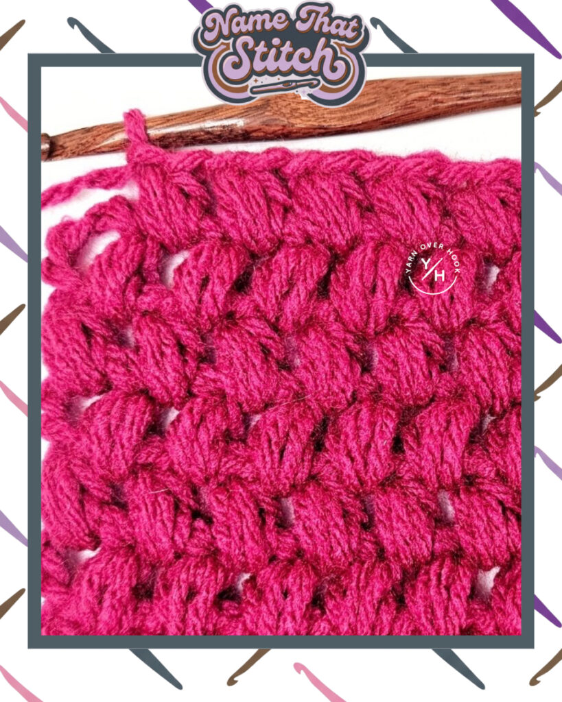 Close-up of a crocheted fabric displaying a repeating stitch pattern worked in dark pink yarn, with a wooden crochet hook and featured as part of the Name That Stitch daily crochet puzzle. View more at NameThatStitch.com