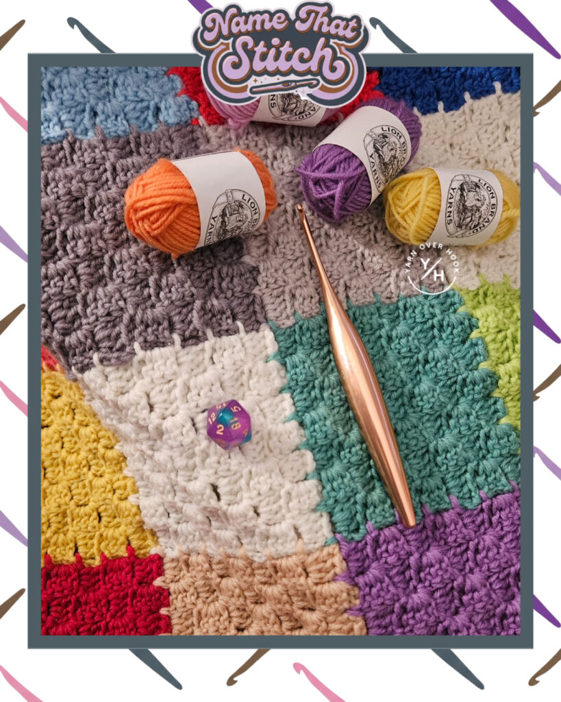 Flat lay of a colorful crochet blanket made of textured stitch squares, with a copper crochet hook, small skeins of yarn in orange, purple, and yellow, and a purple 20-sided die resting on top, styled for the Name That Stitch crochet puzzle. View more at NameThatStitch.com