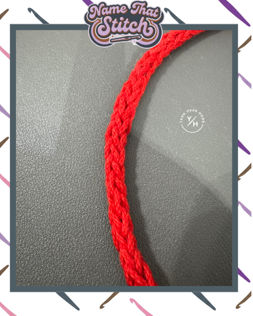 Close-up of a bright red crocheted cord showing a braided, rope-like stitch pattern against a gray background, presented as a Name That Stitch daily crochet puzzle. View more at NameThatStitch.com