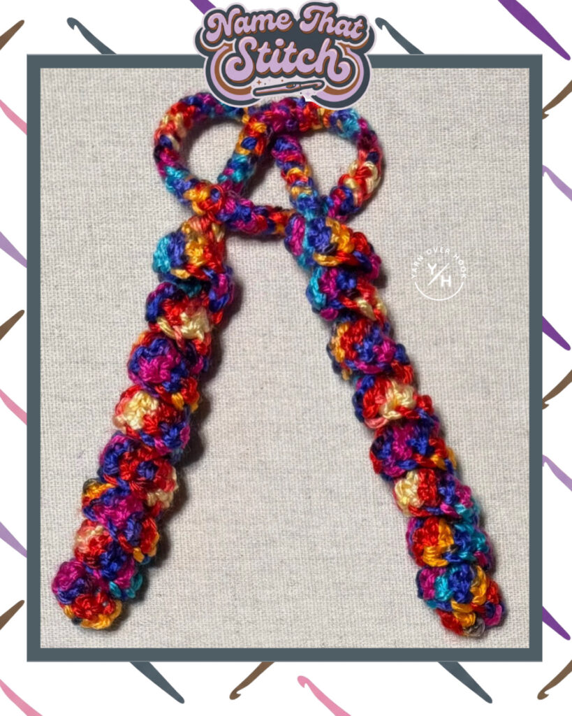 Colorful crochet cord made with multicolored yarn, tied into a bow shape, featuring tightly clustered, textured stitches for a Name That Stitch daily crochet puzzle. View more at NameThatStitch.com