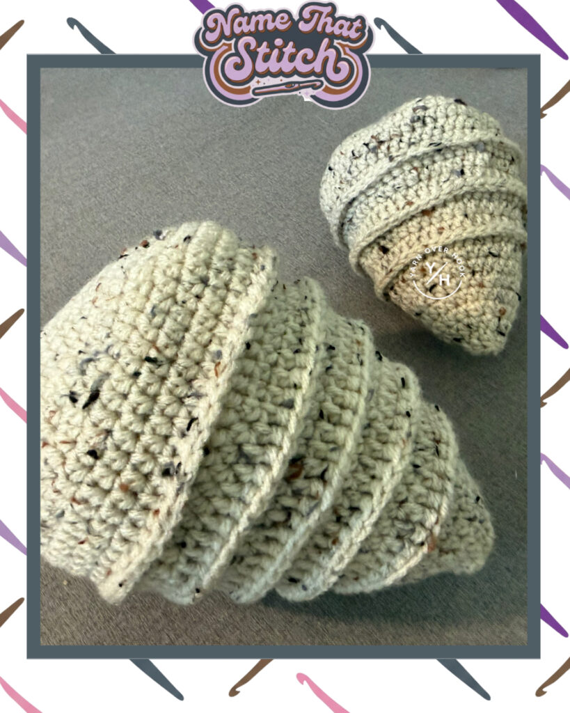 Cream speckled crochet piece shaped like a spiral shell or coiled cone, displayed on a gray background and featured as part of the Name That Stitch daily crochet puzzle. View more at NameThatStitch.com