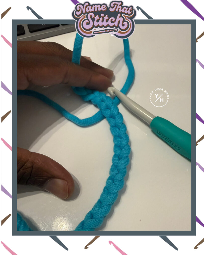 Close-up of bright blue yarn and a crochet hook forming the beginning of a crochet project on a white surface, featured as part of the Name That Stitch daily crochet puzzle. View more at NameThatStitch.com