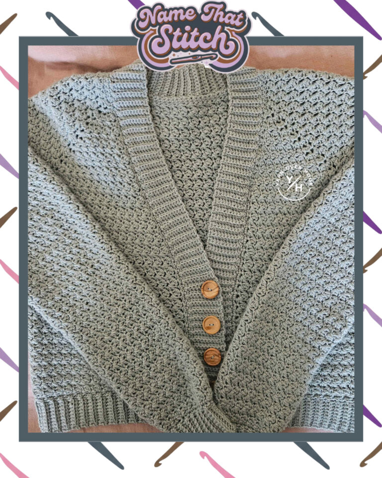 Close-up of a sage green crocheted cardigan displaying a repeating textured stitch pattern with ribbed trim and wooden buttons, featured as part of the Name That Stitch daily crochet puzzle. View more at NameThatStitch.com