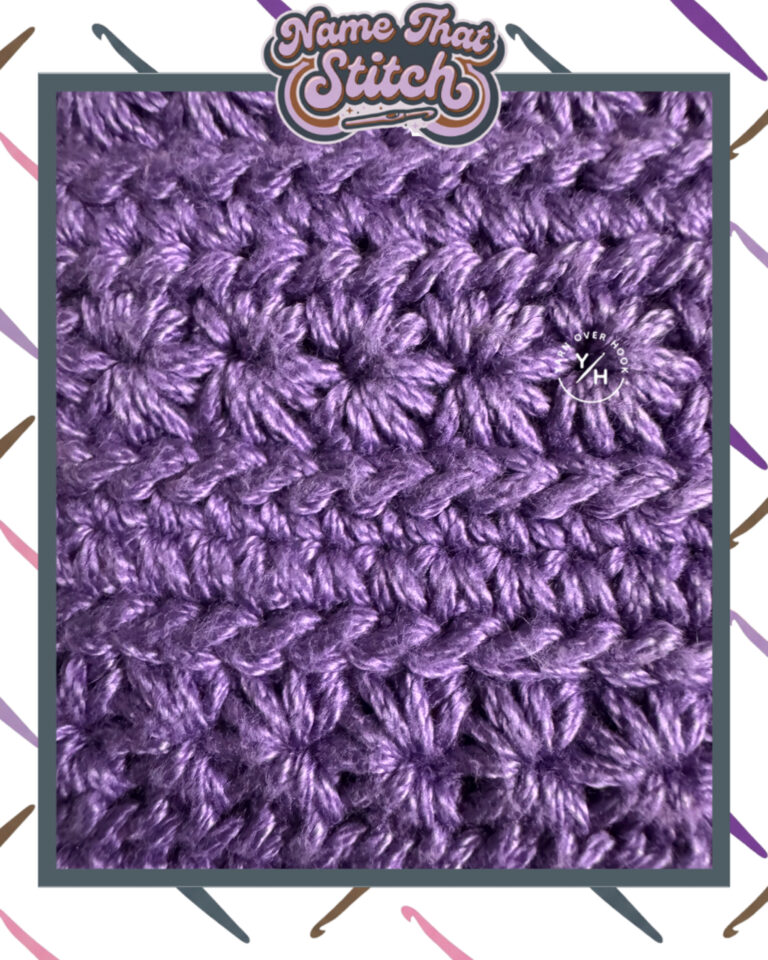 Close-up of a crocheted fabric displaying a repeating flower-like textured stitch pattern worked in purple yarn, featured as part of the Name That Stitch daily crochet puzzle. View more at NameThatStitch.com